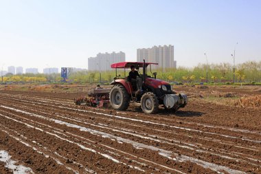 LUANNAN COUNTY, Çin - 27 Nisan 2018: çiftçiler tarım makinelerini bir çiftliğe plastik film fıstığı ekmekte kullanıyorlar, LUANNAN COUNTY, Hebei Eyaleti, Çin