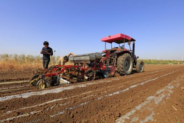 LUANNAN COUNTY, Çin - 27 Nisan 2018: çiftçiler tarım makinelerini bir çiftliğe plastik film fıstığı ekmekte kullanıyorlar, LUANNAN COUNTY, Hebei Eyaleti, Çin