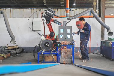 Luannan County, Çin - 21 Haziran 2019: İşçiler Hebei Eyaleti, Çin 'deki Luannan County' deki bir fabrikada akıllı kaynak robotlarının çalışmalarını denetliyor. Şu anda, birçok Çin şirketi çalışmak için akıllı robotlar kullanıyor..