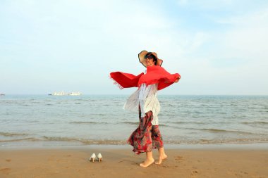 LUANNAN COUNTY, Hebei Eyaleti, Çin - 3 Mayıs 2019: Deniz kenarında kırmızı şallı bir bayan oynuyor.