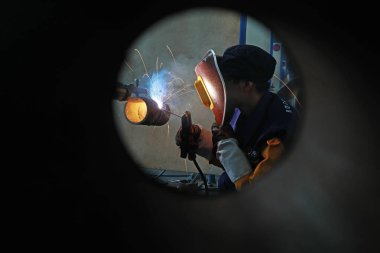LUANNAN COUNTY, Hebei Eyaleti, Çin - 22 Kasım 2019: İşçiler üretim hattında metal parçaları kaynak yapıyorlar.