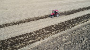 Çiftçiler çiftlikteki tarlayı sürmek için traktör kullanıyorlar.