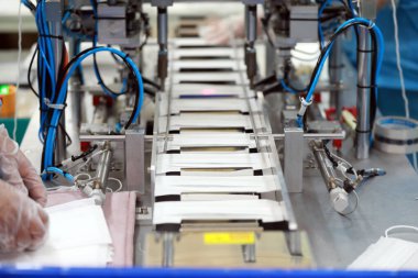 İşçiler tıbbi maske fabrikasının üretim hattında meşguller..