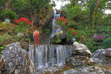 Turistler Pekin 'deki Hongluo tapınağında yapay şelalenin önünde oynuyorlar.