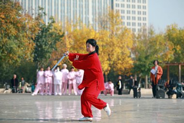 LUANNAN COUNTY, Hebei Eyaleti, Çin - 18 Ekim 2020: Kırmızılı bir kadın meydanda tai chi kılıcı üzerinde çalışıyor