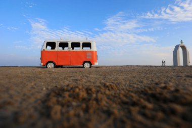 Kırmızı otobüs modeli sahilde manzaralı bir yerde.