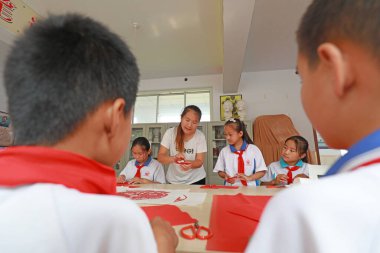 LUANNAN COUNTY, Hebei Eyaleti, Çin - 27 Eylül 2020: Öğretmenlerin rehberliğinde, ilkokul öğrencileri sınıfta kağıt kesme sanatını öğrenirler