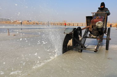 LUANNAN COUNTY, Hebei Eyaleti, Çin - 22 Ocak 2021: Çiftçiler vahşi doğada nehir buzunu kesmek için elektrikli testere kullanıyorlar