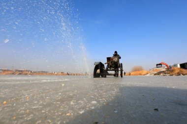 LUANNAN COUNTY, Hebei Eyaleti, Çin - 22 Ocak 2021: Çiftçiler vahşi doğada nehir buzunu kesmek için elektrikli testere kullanıyorlar