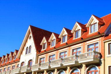 Çatı katı egzotik manzara mimarisi ve mavi gökyüzünün altında küçük tavan arası penceresi.