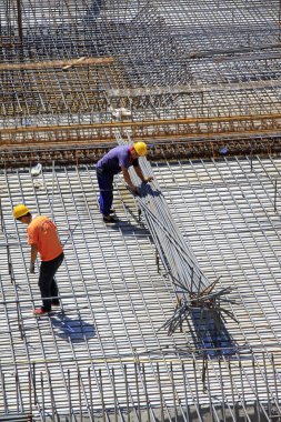 Luannan İlçesi - 21 Ağustos 2015 'te Çin' in Hebei Eyaleti, Luannan ilçesinde inşaat alanında çelik çubuk taşıyan işçiler