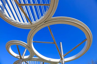 Mavi gökyüzü altında paslanmaz çelik çember mimarisi