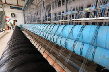 LUANNAN COUNTY, Çin - 19 Temmuz 2021: işçiler Kuzey Çin 'deki bir balıkçı ağı işleme fabrikasında tedirgin bir tezgah üzerinde çalışıyorlar