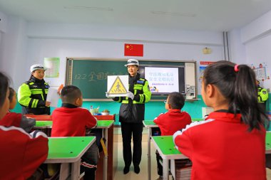 LUANNAN COUNTY, Çin - 30 Kasım 2021: Bir kadın trafik polisi Kuzey Çin 'deki ilkokul öğrencilerine trafik sinyal simgelerinin anlamını açıklar