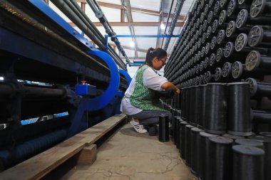 LUANNAN COUNTY, China - July 19, 2021: workers work nervously on a loom at a fishing net processing plant in North China clipart