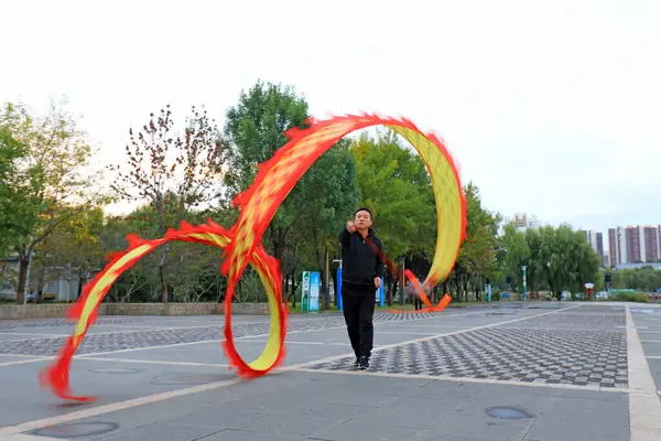 stock image LUANNAN COUNTY, China - October 10, 2021: people are waving ribbons to exercise in the park, North China