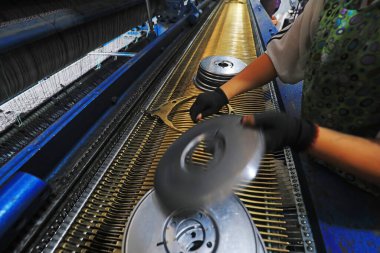 Workers replace shuttle cores at a fishing net processing plant, China clipart