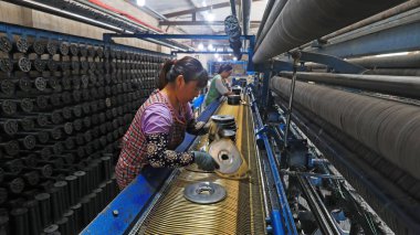 LUANNAN COUNTY, China - July 19, 2021: workers replace shuttle cores at a fishing net processing plant, China clipart