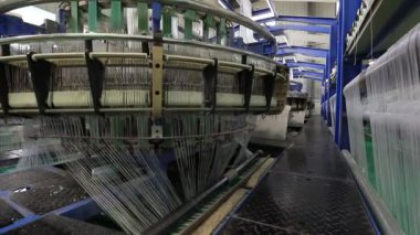 Yüksek hızlı dönen plastik dokuma makineleri Kuzey Çin 'de bir üretim atölyesinde.