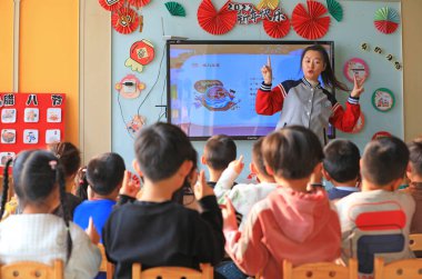 LUANNAN COUNTY, Çin - 7 Ocak 2022: anaokulu öğretmenleri çocuklara Laba çocuk şarkıları söylemeyi öğretiyor, Kuzey Çin