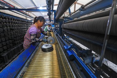 LUANNAN COUNTY, China - July 19, 2021: workers replace shuttle cores at a fishing net processing plant, China clipart