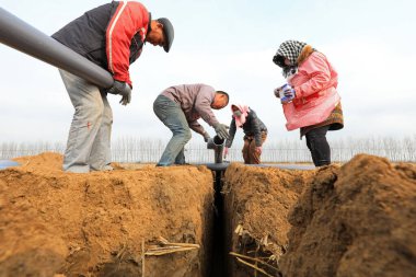 LUANNAN, Çin - 18 Mart 2022: İşçiler su tasarrufu boru hatları döşüyorlar ve yüksek standartlı tarım arazisi inşaat projeleri uyguluyorlar, Kuzey Çin