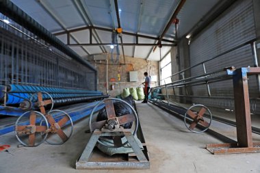 LUANNAN COUNTY, Çin - 30 Ağustos 2021: İşçiler Kuzey Çin 'deki bir işleme tesisinde ağ örme ekipmanları taşıyorlar