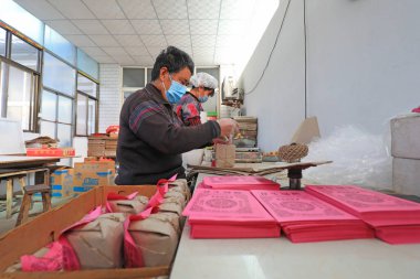 LUANNAN COUNTY, Çin - 19 Ocak 2022: işçiler Çin 'in kuzeyindeki bir fabrikada geleneksel bir Çin lezzeti olan gevrek şeker paketliyorlar.