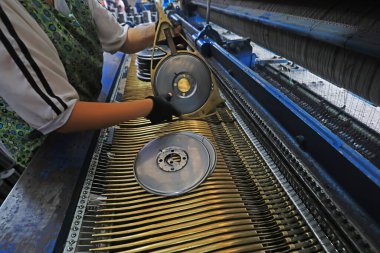 Workers replace shuttle cores at a fishing net processing plant, China clipart