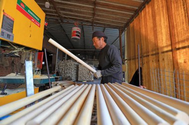 LUANNAN COUNTY, China - November 25, 2021: workers process wooden spade handles in a factory, North China clipart