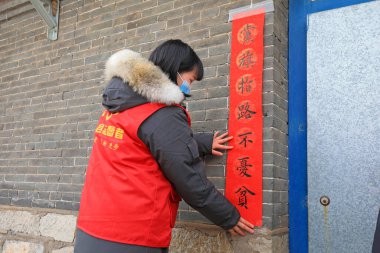 LUANNAN COUNTY, China - January 24, 2022: farmers post red couplets at the door on the eve of the Spring Festival clipart