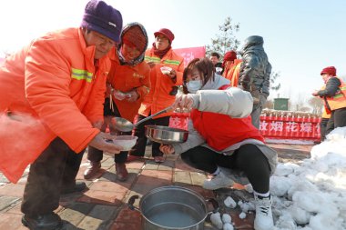 LUANNAN COUNTY, Çin - 14 Şubat 2022: Genç gönüllüler, Fener Festivali arifesinde Kuzey Çin 'deki temizlik işçilerine buharlı börek dağıtıyor.