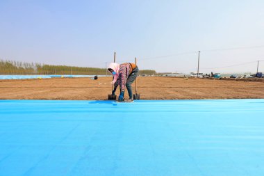 LUANNAN COUNTY, Çin - 14 Nisan 2022: Çiftçiler, sıcaklığı ve nemi korumak için pirinç filizleme tepsisini dokumasız kumaş ve plastik film ile kaplıyorlar.