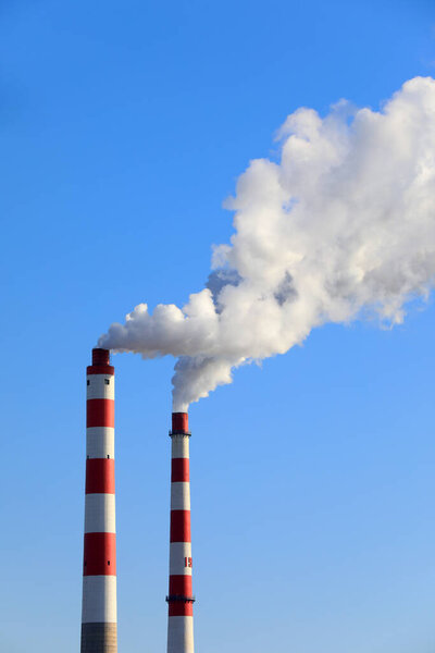 The chimney that emits smoke and dust in the blue sky