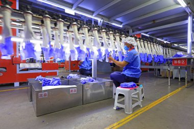 LUANNAN COUNTY, Çin - 22 Nisan 2021: işçiler yoğun bir şekilde Kuzey Çin 'deki bir fabrikada nitril eldiven üretim hattı üzerinde çalışıyorlar.