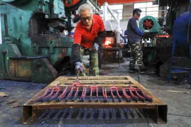 LUANNAN COUNTY, China - September 24, 2021: workers work intensively on a forging production line in a hardware tool production factory in North China clipart