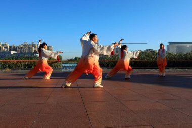 LUANNAN COUNTY, Çin - 21 Eylül 2021: İnsanlar parkın ahşap platformunda Tai Chi kılıcı uyguluyorlar, Kuzey Çin