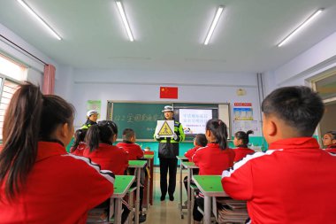 LUANNAN COUNTY, China - November 30, 2021: a female traffic policeman explains the meaning of traffic signal icons to primary school students in North China clipart