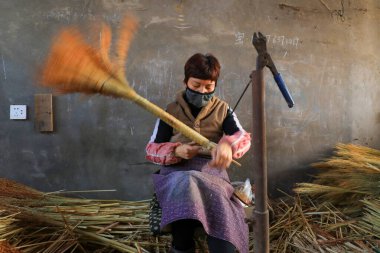 LUANNAN COUNTY, China - December 14, 2021: Farmers are processing brooms in a manual processing workshop, North China clipart