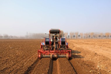 LUANNAN COUNTY, Çin - 9 Mart 2022: Çiftçiler tarlaları düzenlemek ve Kuzey Çin 'deki tarlada Çin lahanası ekmeye hazırlanmak için tarım makineleri sürüyorlar