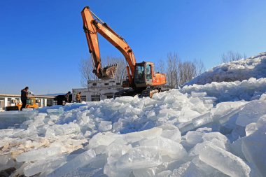 LUANNAN COUNTY, Çin - 17 Ocak 2022: çiftçiler buz küplerini ayırıyorlar ve onları büyük buz yığınları haline getiriyorlar, Kuzey Chin
