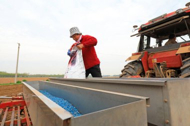 LUANNAN COUNTY, Çin - 26 Nisan 2021: Çiftçiler ekiciye gübre ve tohum ektiler, Kuzey Çin.