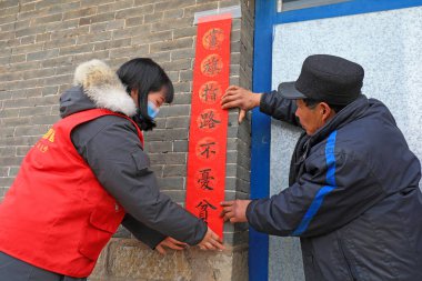 LUANNAN COUNTY, China - January 24, 2022: farmers post red couplets at the door on the eve of the Spring Festival clipart