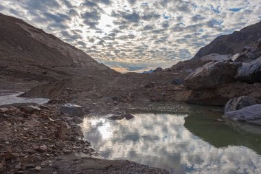 Gün batımında eriyen Vallelunga buzulunun oluşturduğu küçük göl ve akarsu. Küresel ısınma nedeniyle buzullar hızla geri çekiliyor, Alto Adige, İtalya