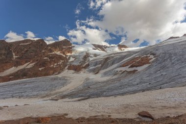 Barba dOrso glacier flowing over red mountain rocks. The glacier is in rapid retreat caused by global warming. Vallelunga, Alto Adige, Italy. Popular mountain with climbers