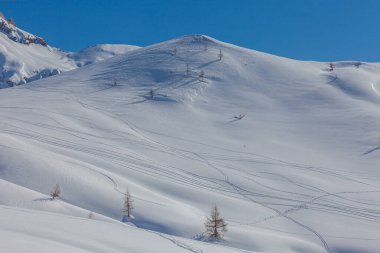 Giau Pass, Dolomites, İtalya 'nın beyaz karlı çayırlarında kayakçı ve snowboardcu izleri var.