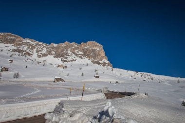 Nuvolau Dağı 'nın heybetli kayalık duvarının altından geçen bir Dolomite yolunun kış manzarası. Giau Geçidi, Belluno, İtalya