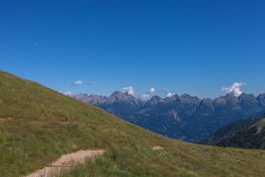 Latemar Massif 'in güney tarafındaki çayırların ortasındaki patika. Arkadaki Lagorai sıradağları. UNESCO dünya mirası sahası, Trentino-Alto Adige, İtalya, Avrupa