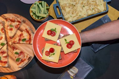 Erkek el ele tutuşma tabağında pizza ve makarna manzaralı aperatifler var.