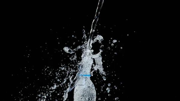 Abstract water jet crashes on a black background from a plastic bottle